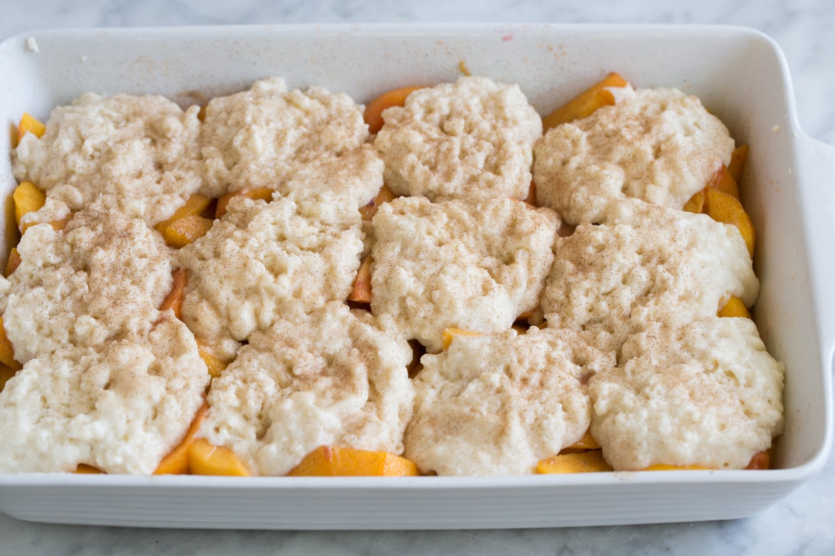 Prepared cobbler with cinnamon sugar topping, shown before baking in oven.