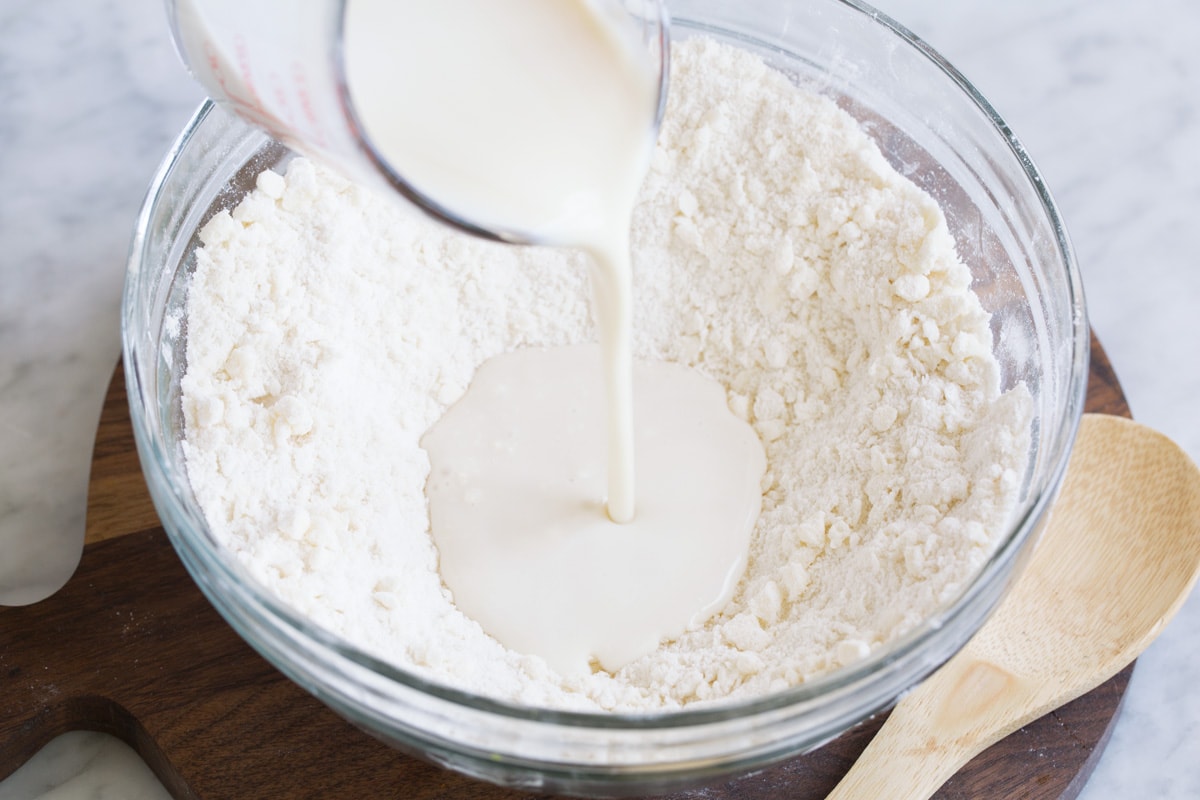 Pouring buttermilk into well in flour mixture.