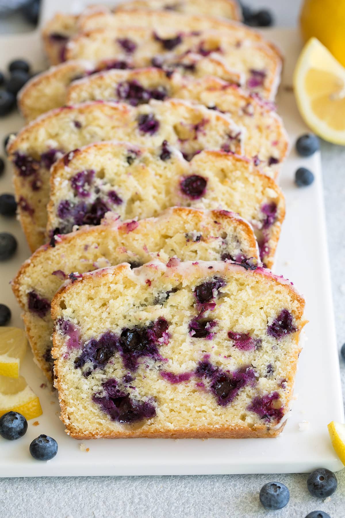 slices of glazed lemon blueberry bread on white platter