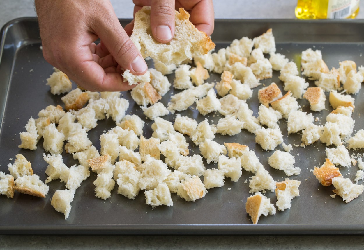 Caesar Salad making homemade croutons tearing small pieces of fresh bread
