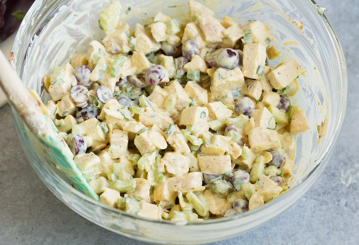 Curry Chicken Salad tossed together with dressing in bowl