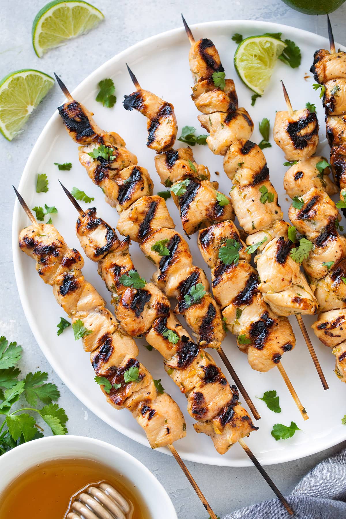 honey lime chicken skewers on white plate with lime wedges