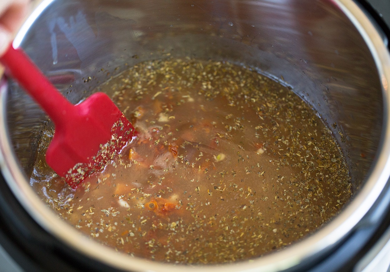 Instant Pot Tuscan Chicken Pasta mixing broth and sun dried tomatoes