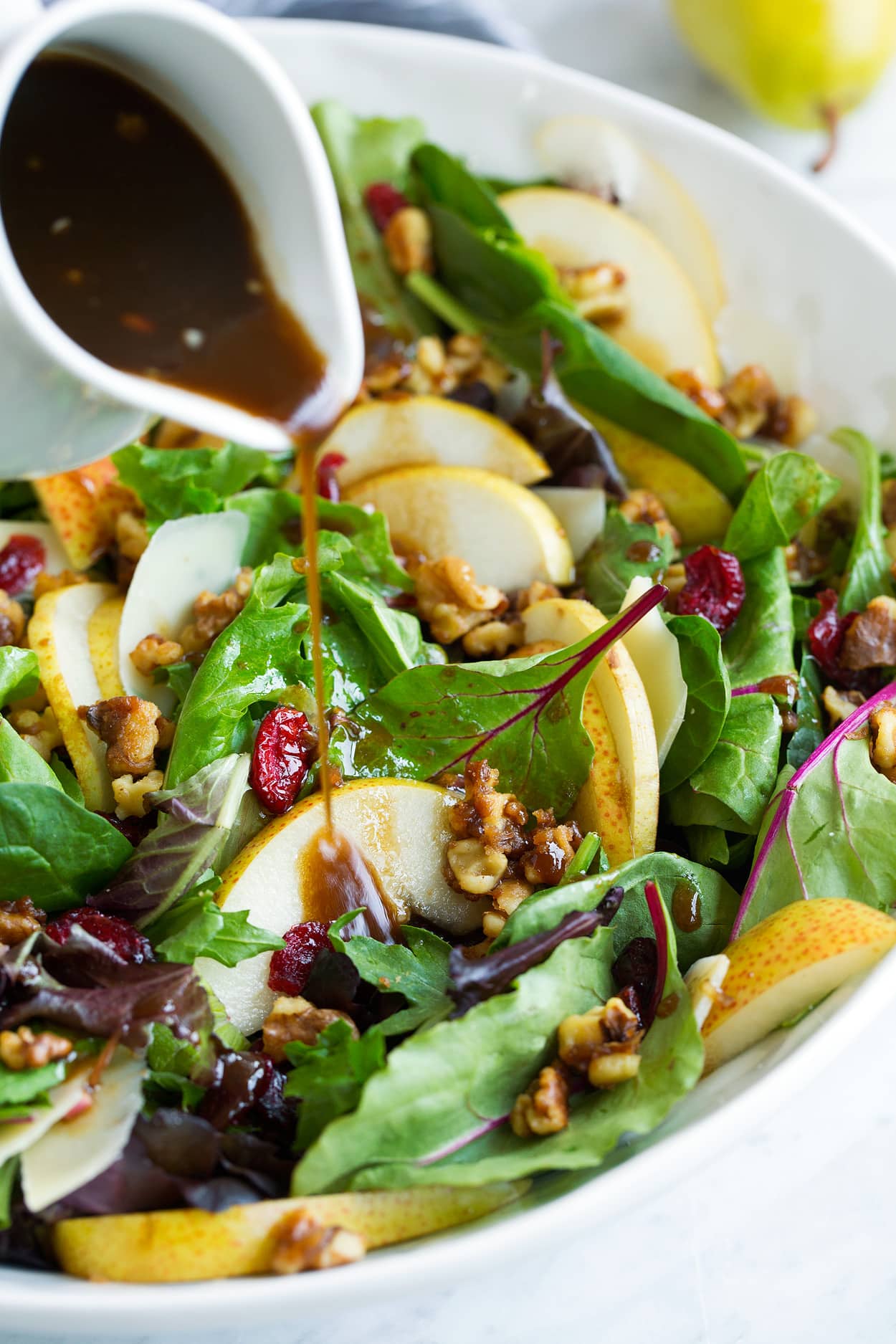 Pouring Balsamic Vinaigrette over Pear Salad in Salad Bowl