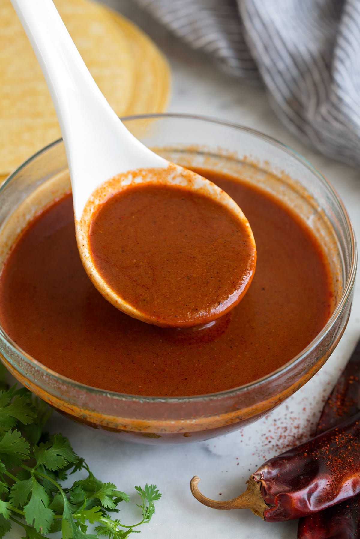 a ladle of Enchilada Sauce over a glass bowl