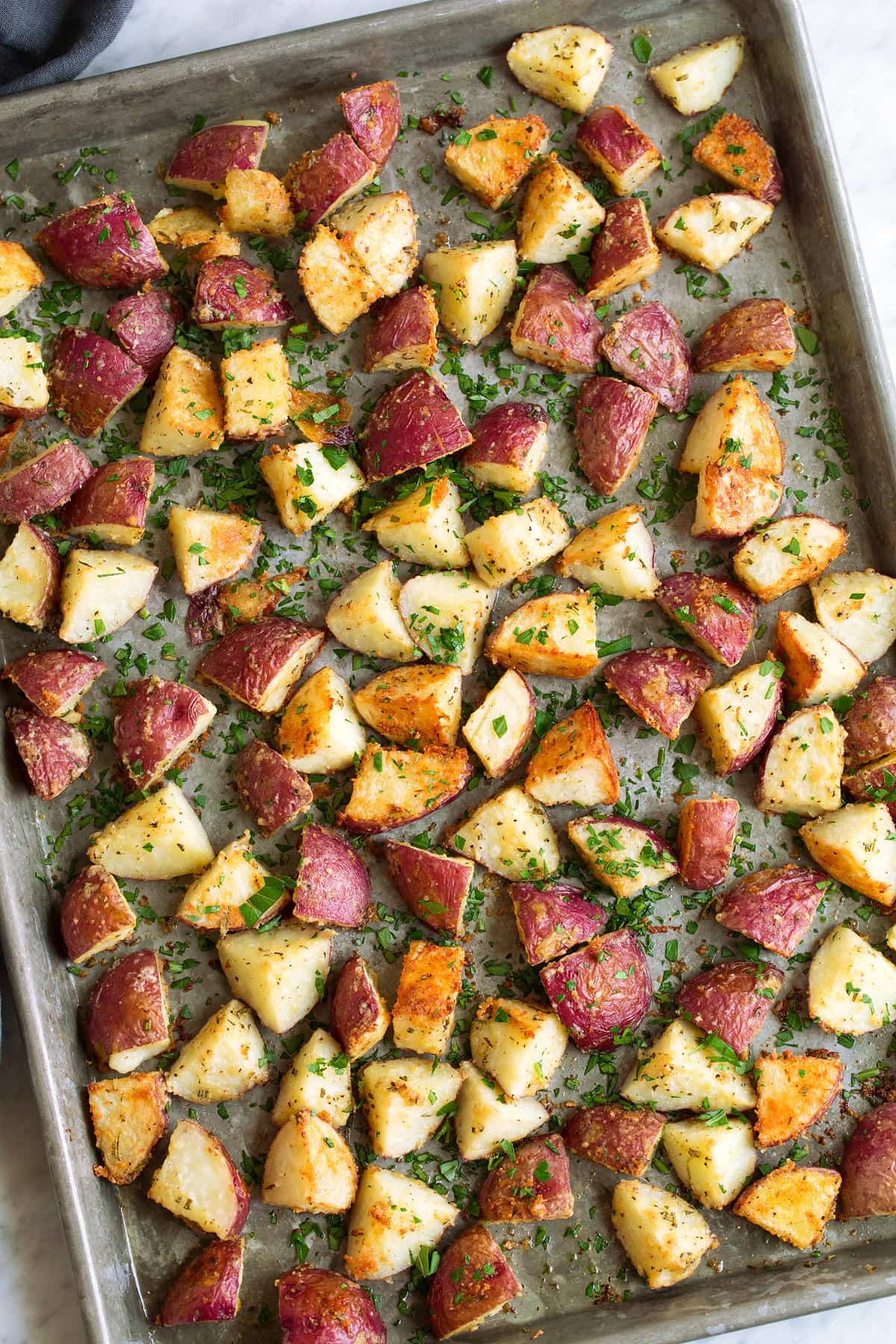 Overhead image of roasted red potatoes spread across baking sheet.