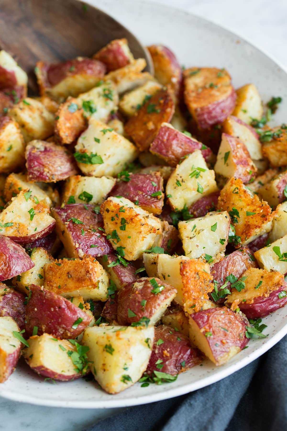 garlic Roasted Potatoes with a parmesan crust and fresh parsley in a serving bowl.