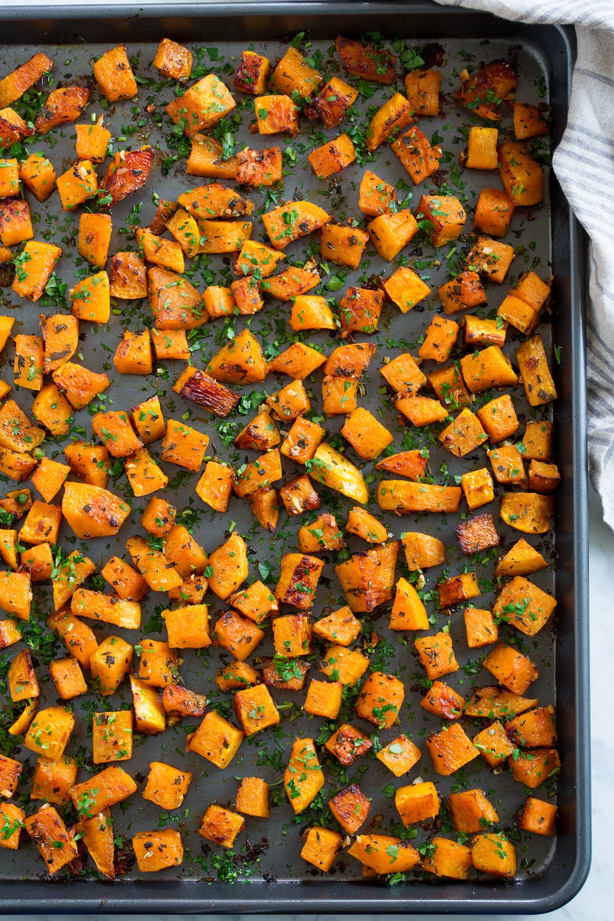 Roasted Butternut Squash on a dark baking sheet after roasting.