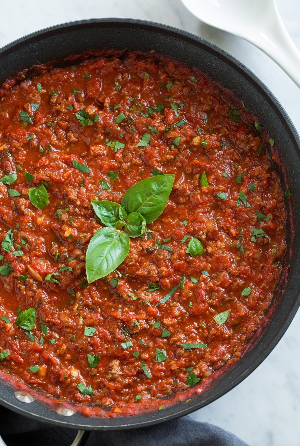 Overhead close up image of the best spaghetti sauce from scratch in a skillet with basil leaves in the center.