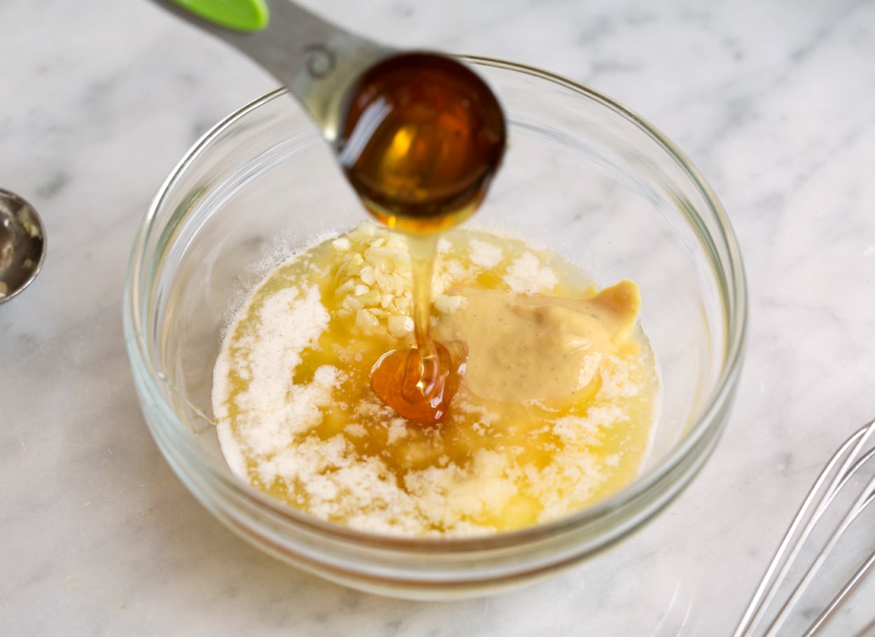 Mixing sauce ingredients in a mixing bowl for baked salmon. 
