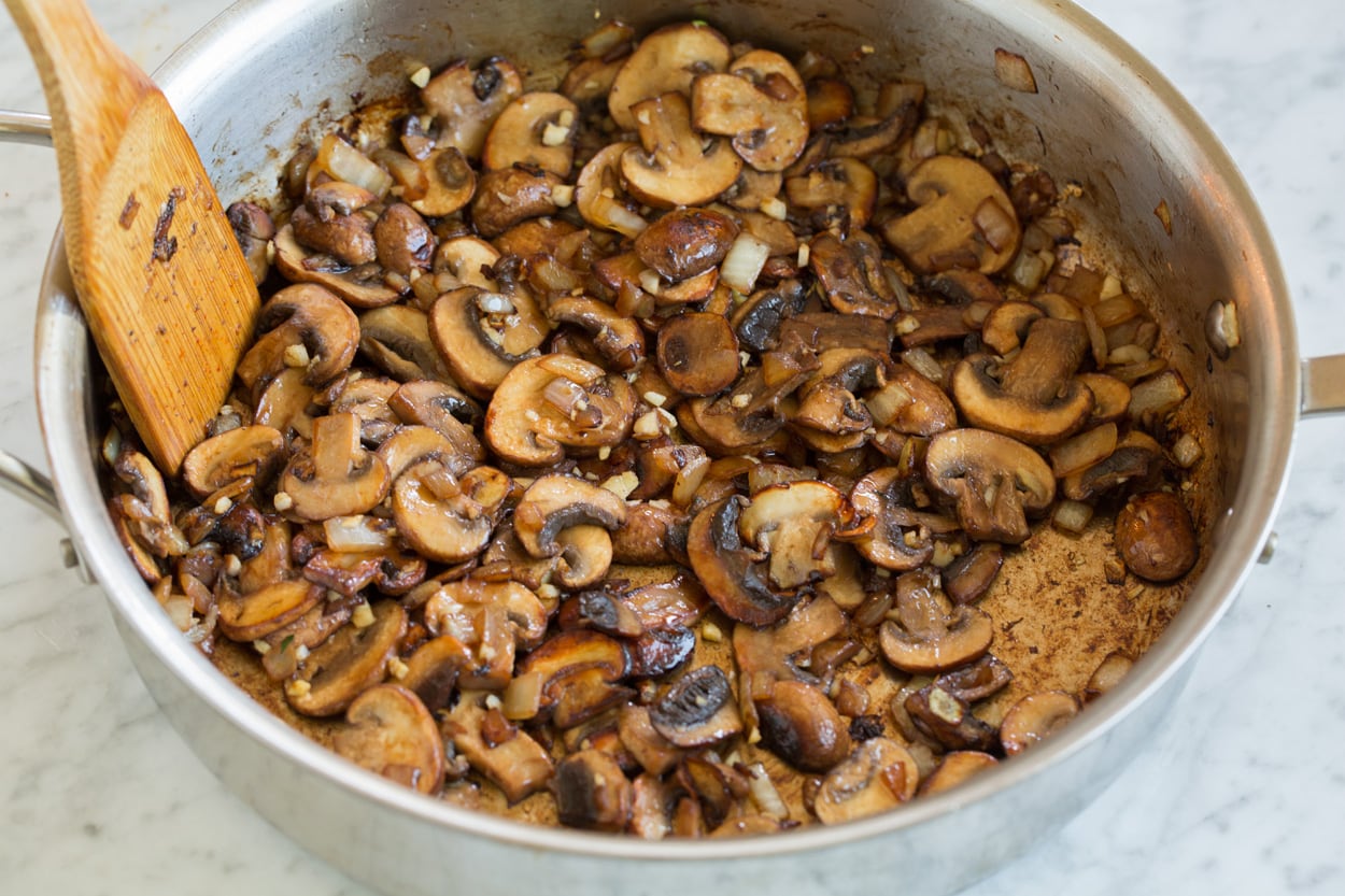 Sauteeing mushrooms and onions in a saute pan for beef stroganoff