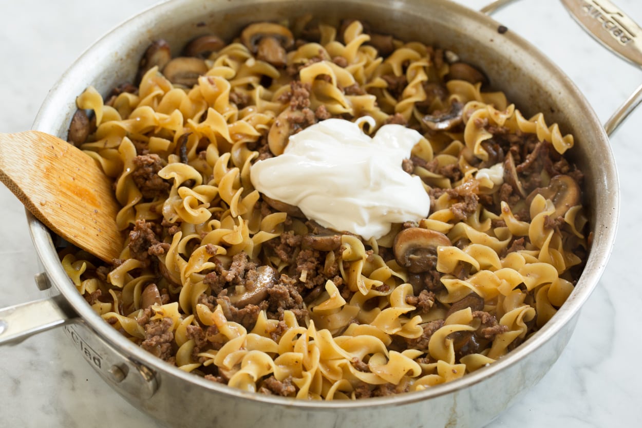 Adding sour cream to beef stroganoff in saute pan