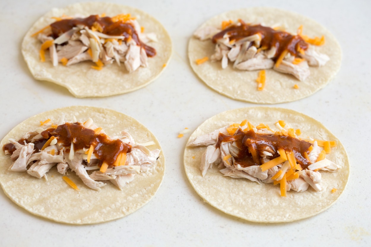 Shown here layering chicken cheese and enchilada sauce on to tortillas for enchiladas