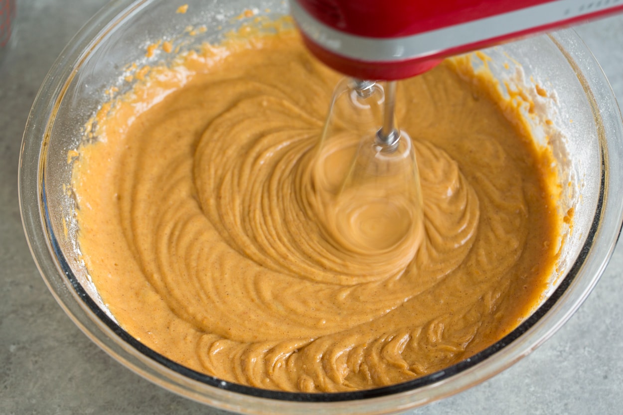 Pumpkin Cake shown here blending mixture in mixing bowl with electric hand mixer
