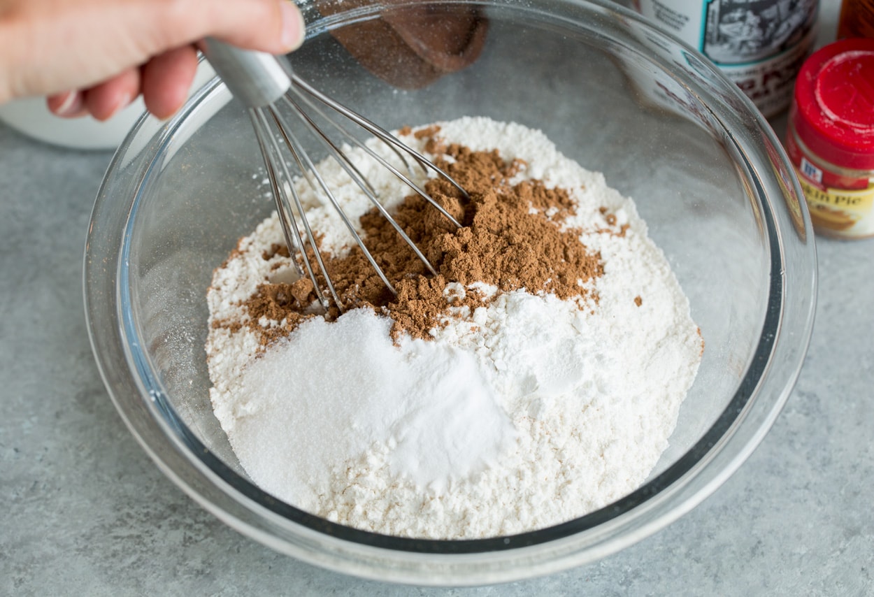 Pumpkin cake shown here whisking flour leaveners and spices in mixing bowl