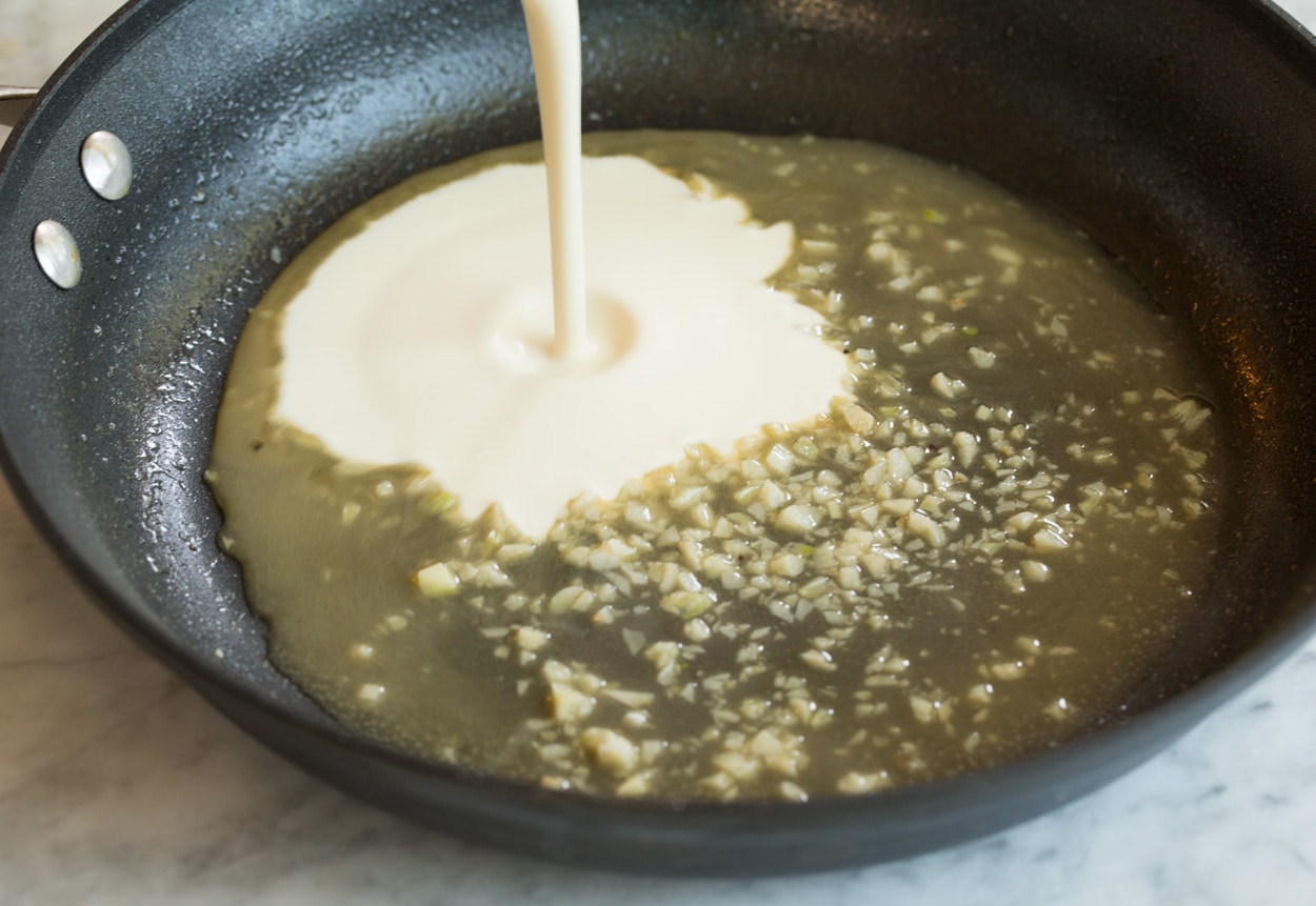Making pan seared salmon mixing chicken broth and heavy cream mixture in skillet.