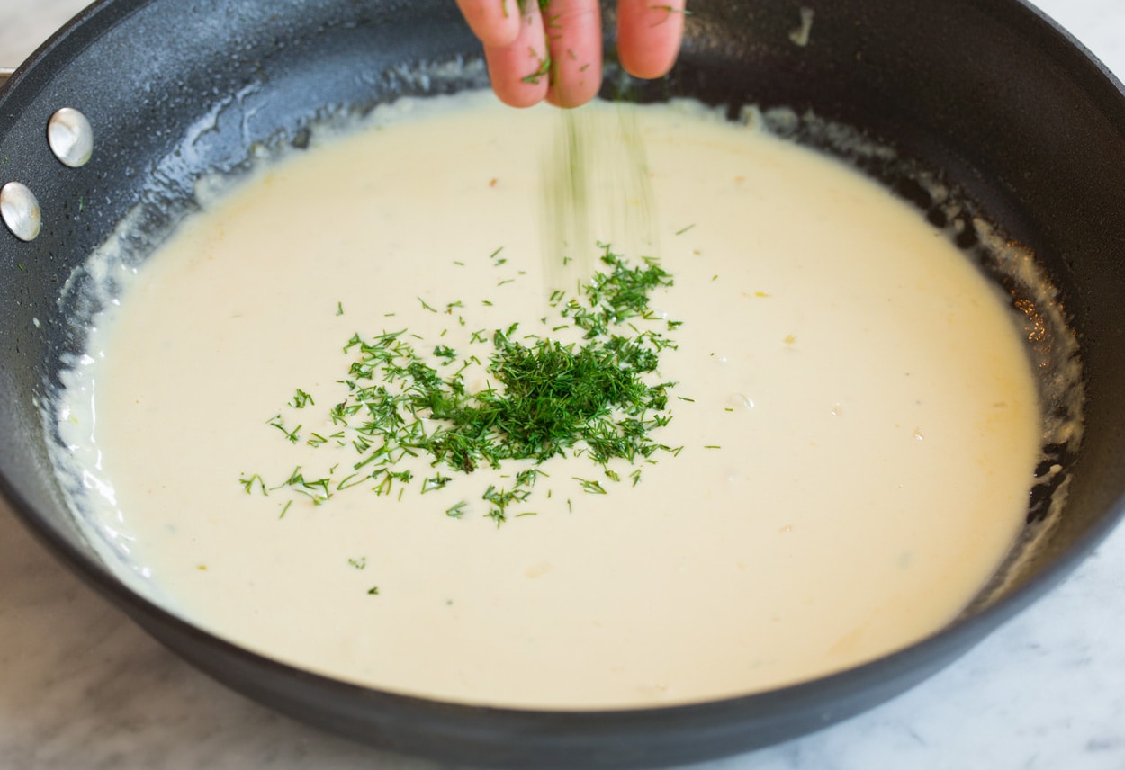 Adding dill to sauce in skillet for pan seared salmon.