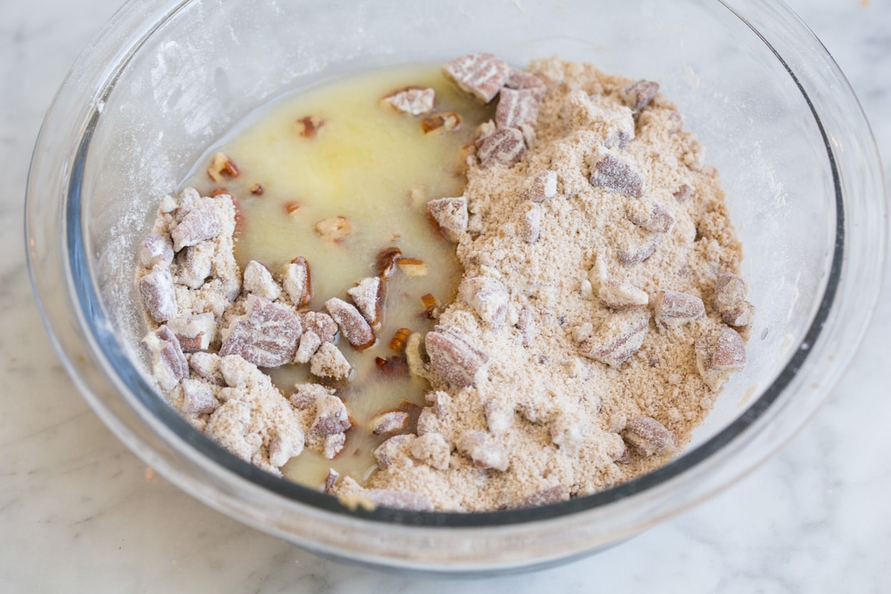 Adding butter to topping mixture in glass bowl, for sweet potato casserole.