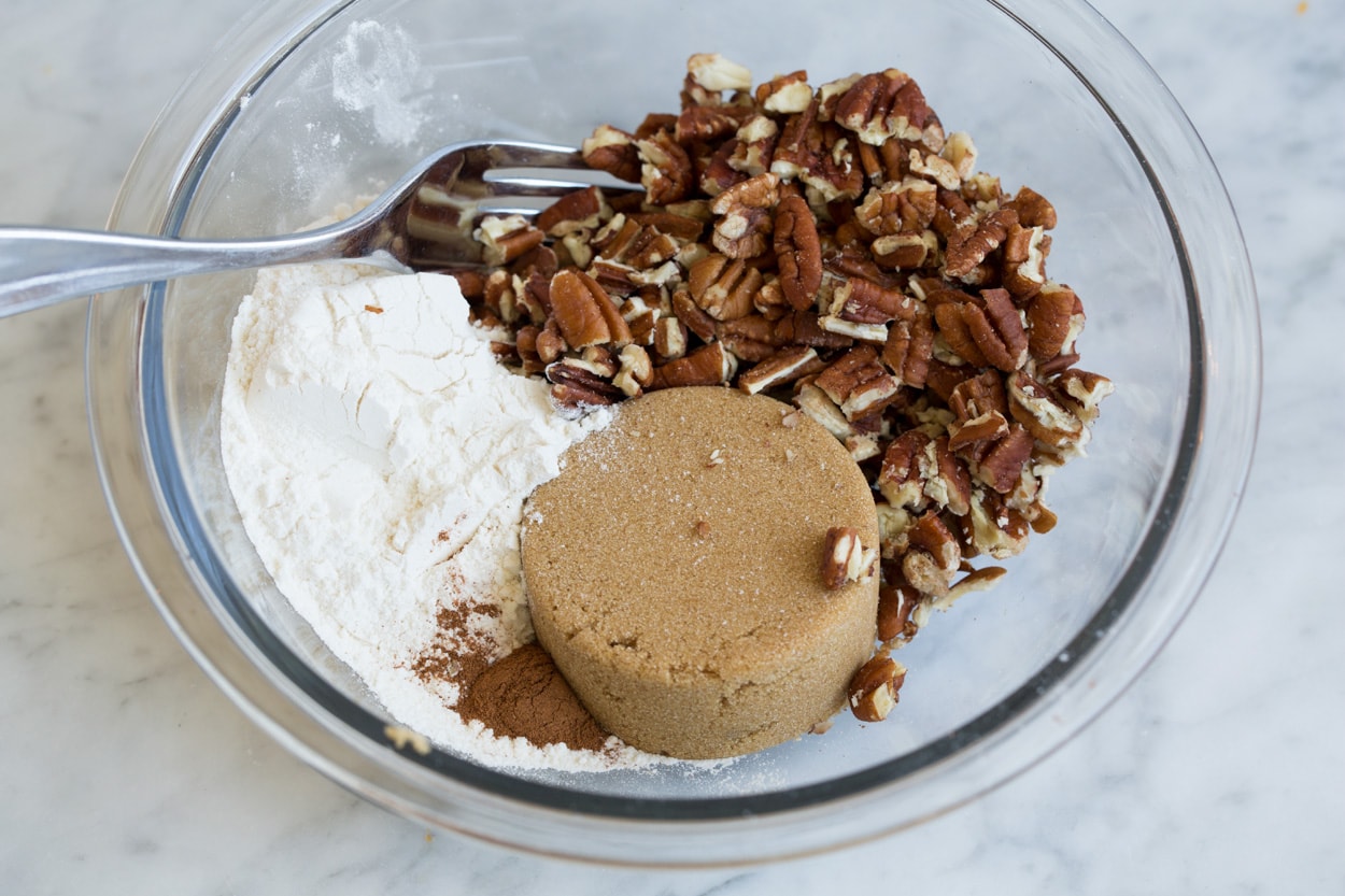Mixing pecans, flour, brown sugar in small glass mixing bowl for sweet potato casserole topping.
