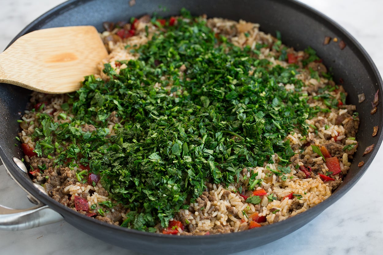 Adding parsley and cilantro to Chimichurri Beef and Rice after cooking.