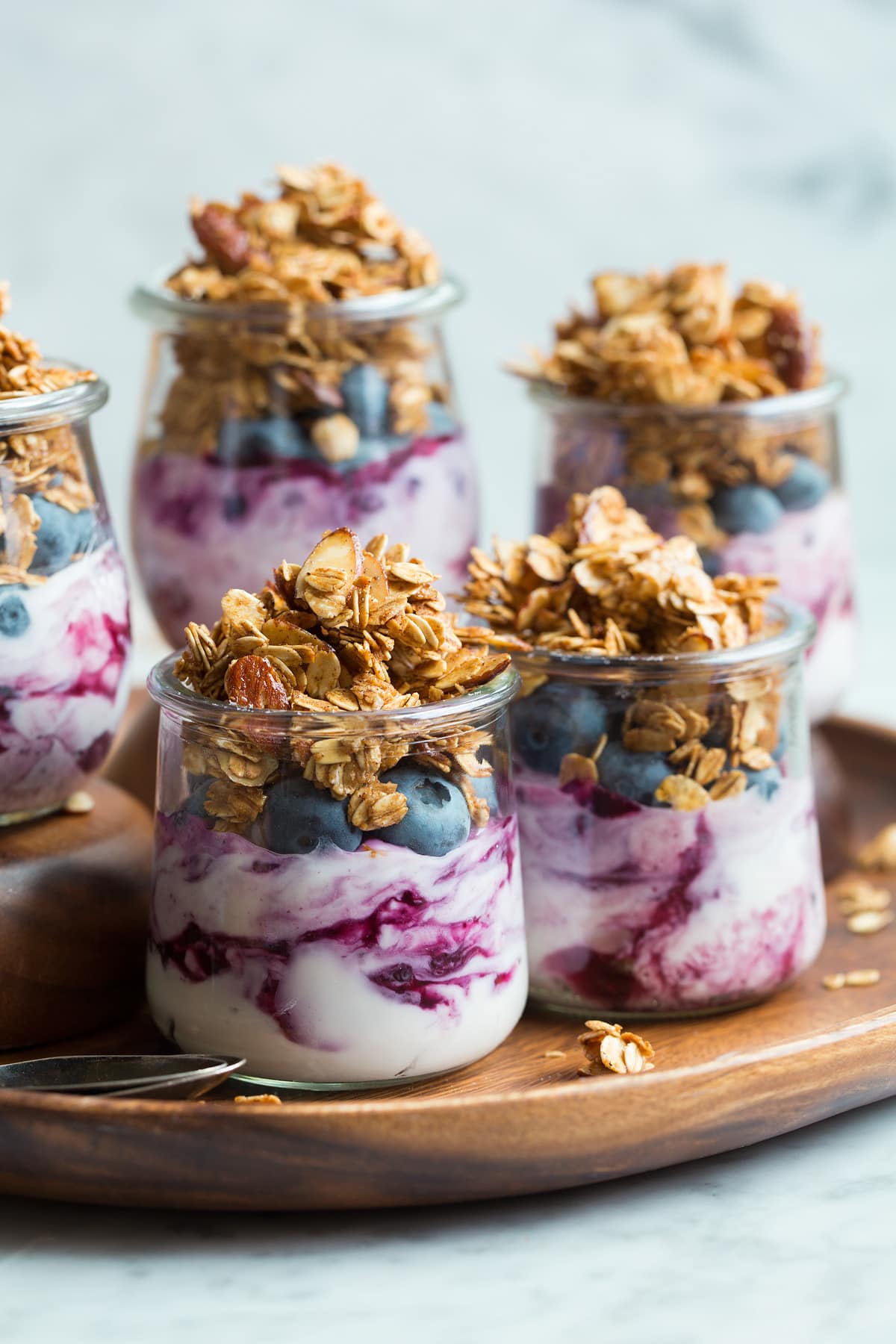 Homemade granola served in small glass cups with yogurt and blueberries.