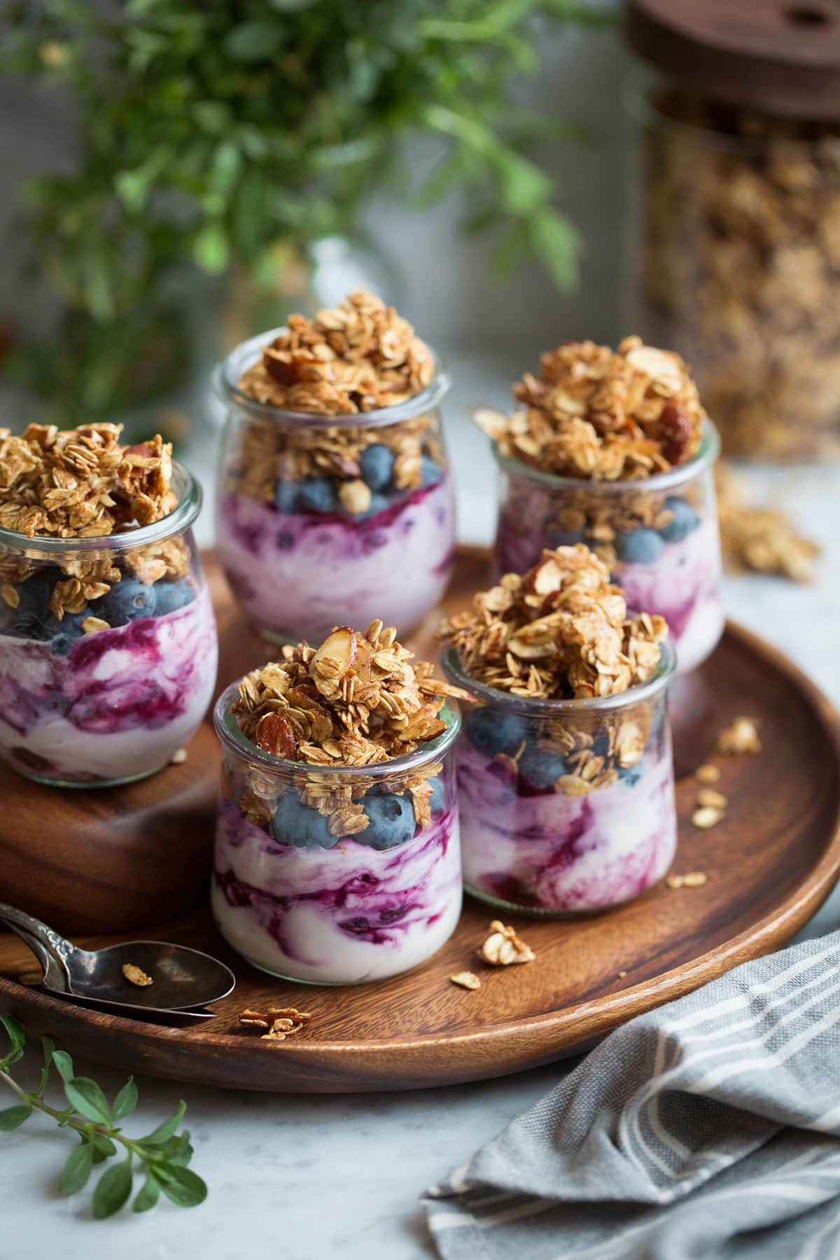 Five servings of granola, yogurt and berries in glass jars.