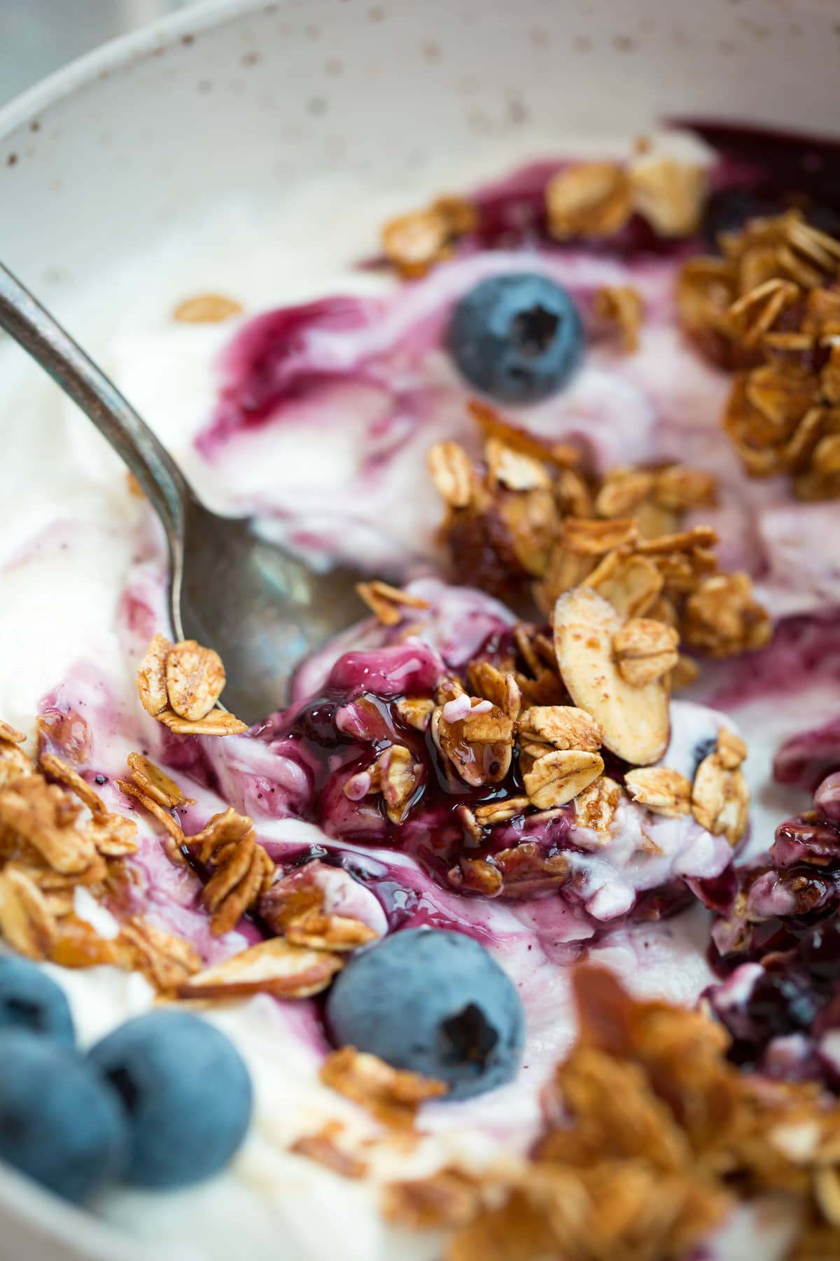 Close up image of granola with yogurt, berries and blueberry sauce.