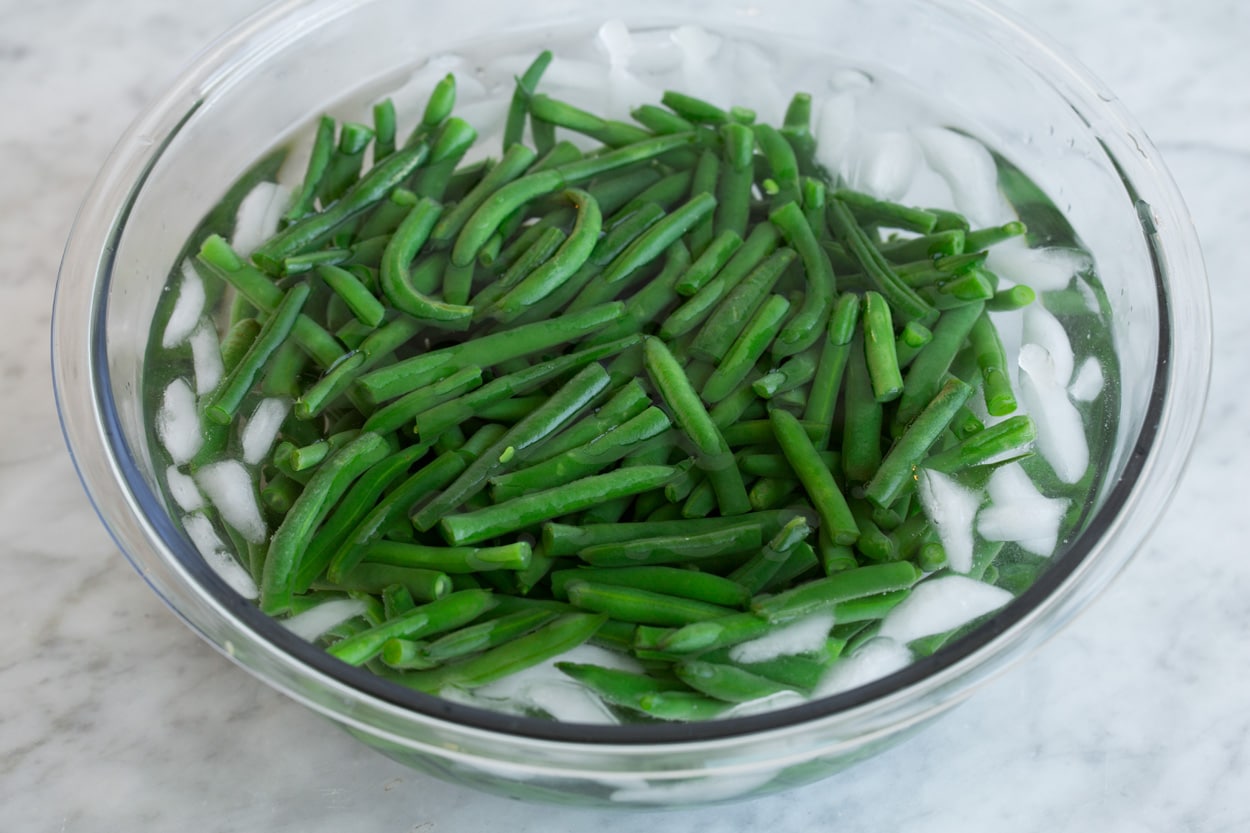 Green beans in an ice water in a glass bowl after draining. 