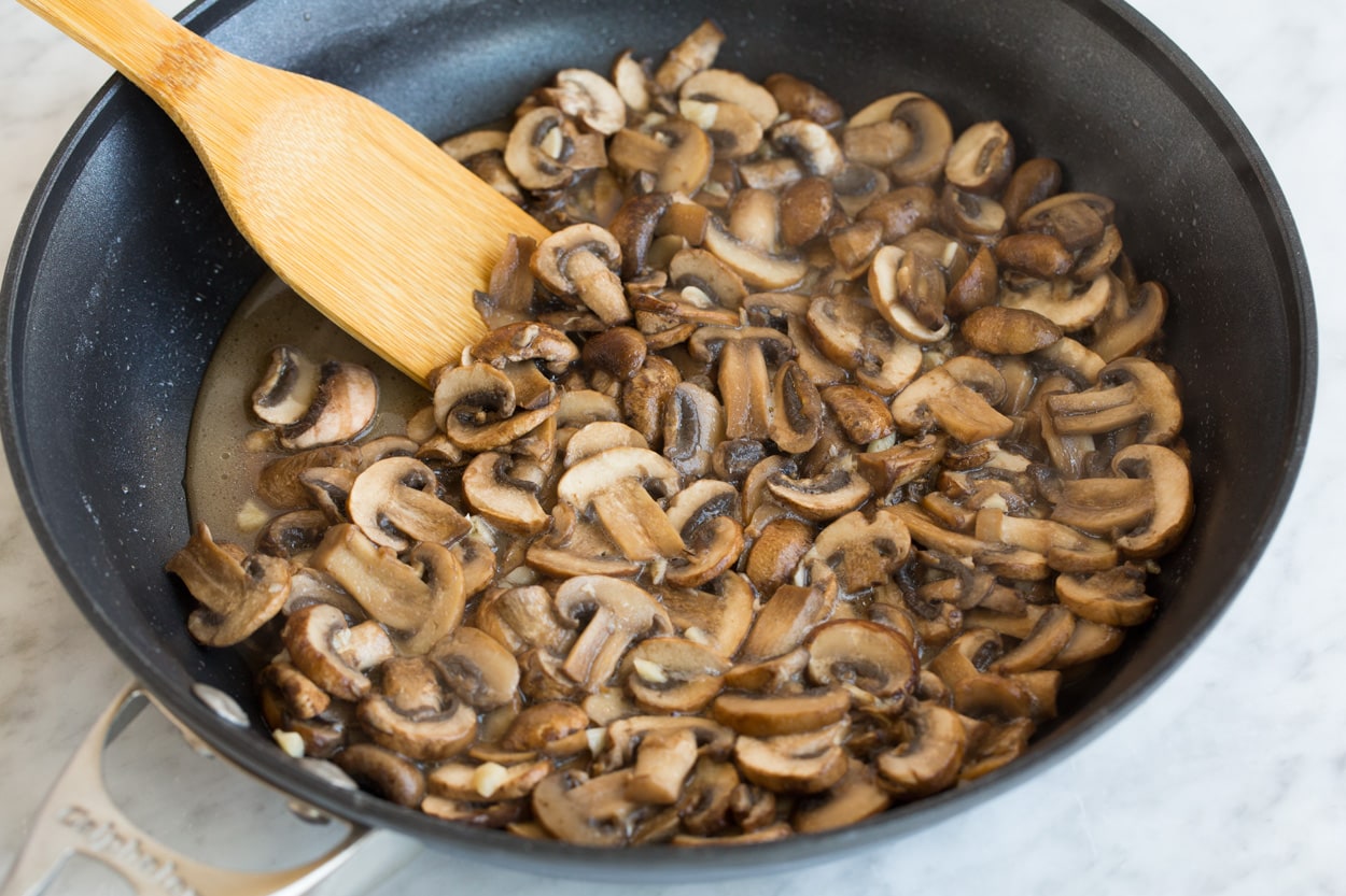 Sauteeing mushrooms in a large dark non-stick skillet for green bean casserole.