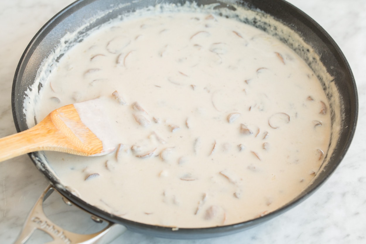 Finished creamy filling in a large skillet set over a marble surface, for Green Bean Casserole.