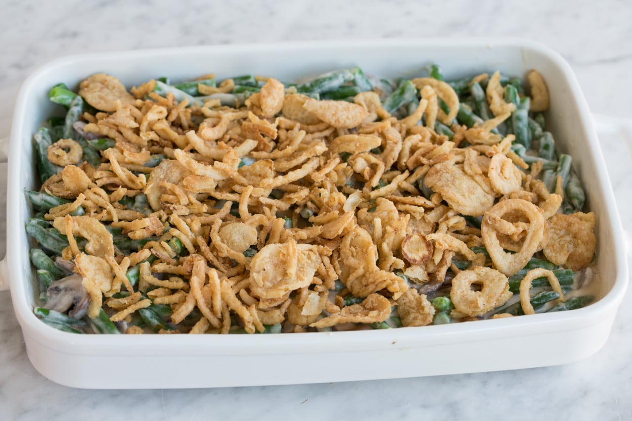 Adding crispy fried onions to Green Bean Casserole before baking.