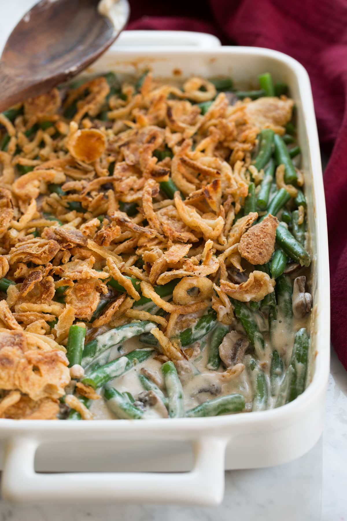 Green Bean Casserole in a white ceramic baking dish with a scoop removed to show filling.