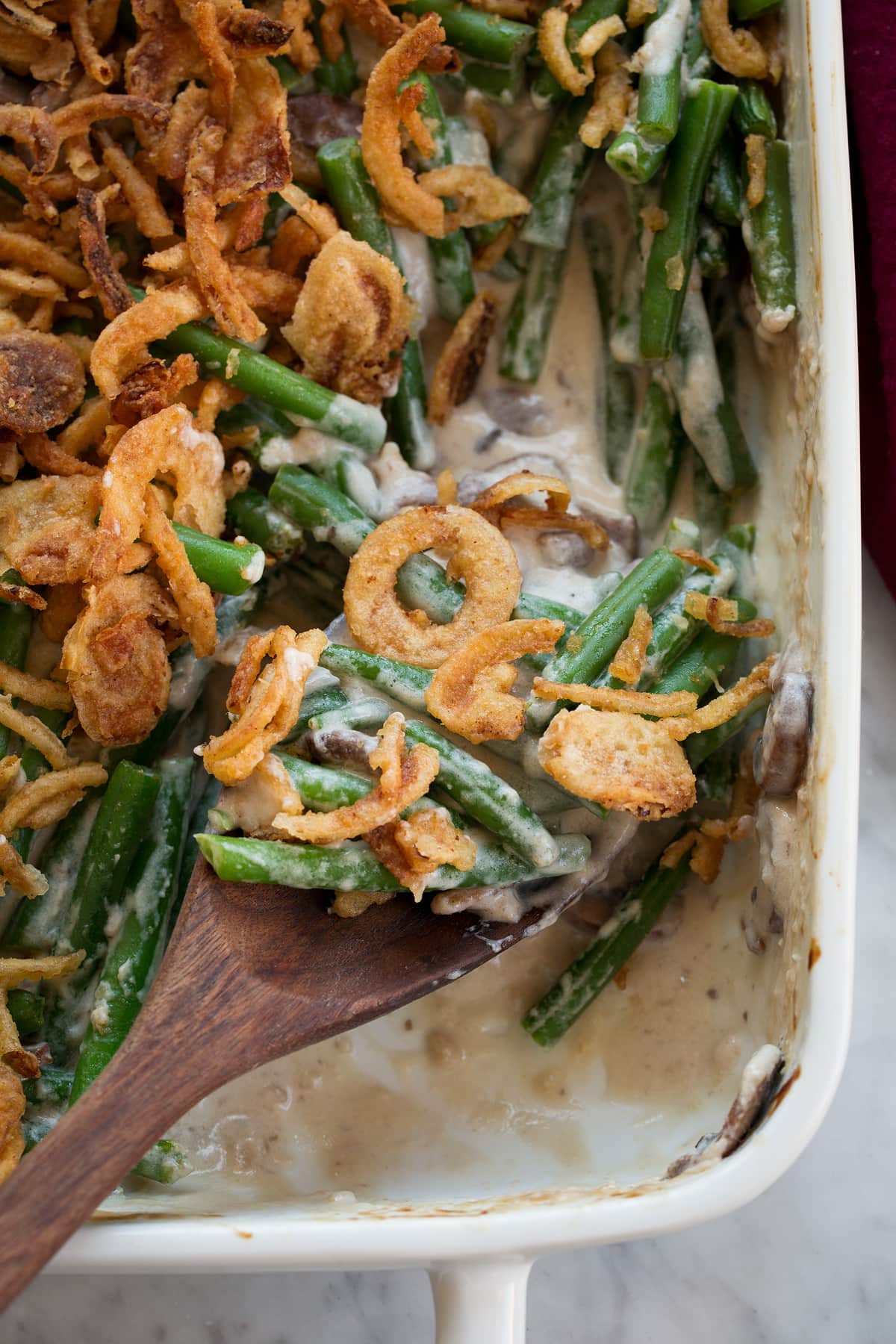 Close up image of scoop of green bean casserole on a wooden spoon.