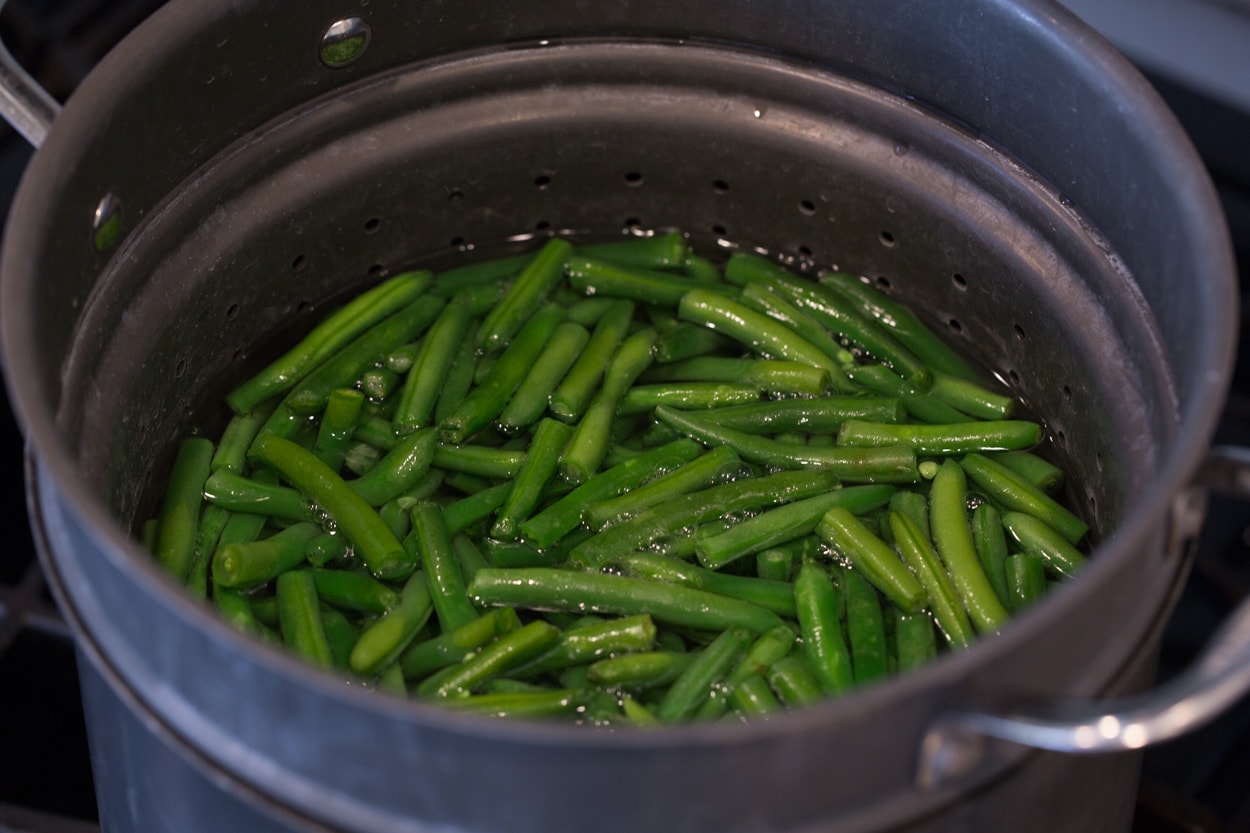 Showing how to make green bean casserole. Start by boiling green beens in pot of water.
