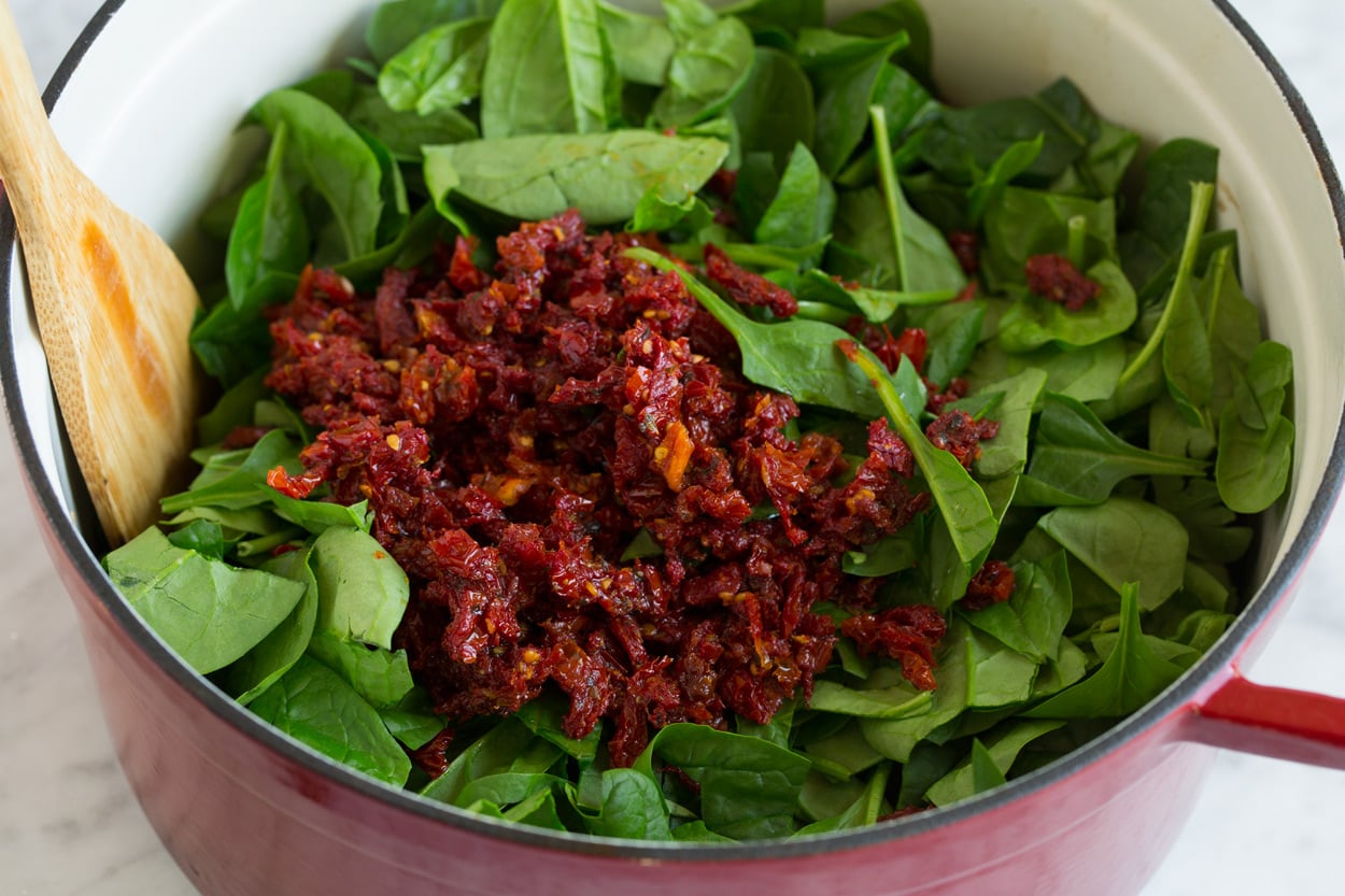 chopped sun dried tomatoes and fresh spinach in large pot