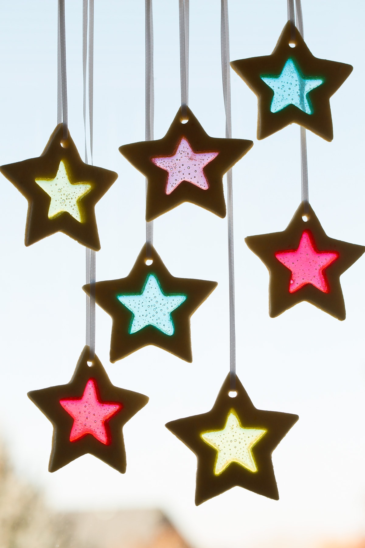 Stained Glass Cookies hanging from ribbon in a window.
