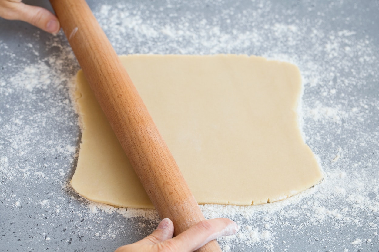 Showing how to make stained glass cookies. Rolling dough out on floured surface for stained glass cookies.