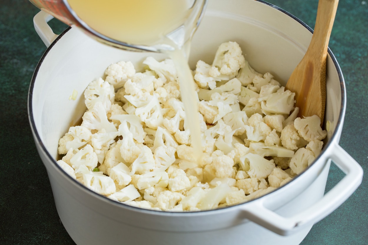 Adding cauliflower and chicken broth to Cauliflower Soup.