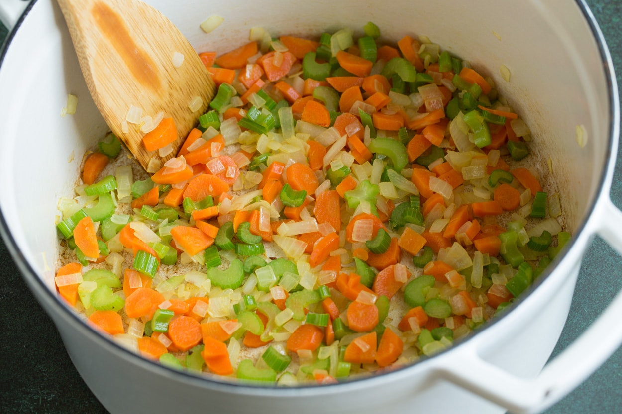 Showing how to make Cauliflower Soup. Sautéing carrots, celery, onions and garlic in pot.