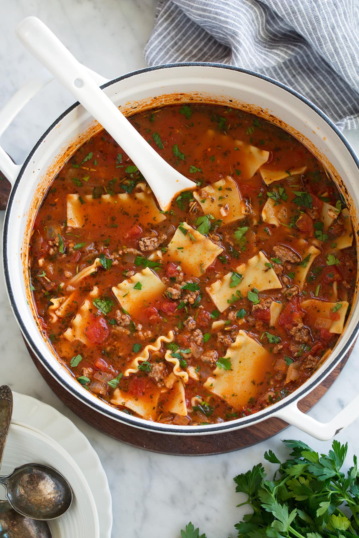 Overhead image of lasagna soup in large white pot set over marble surface.