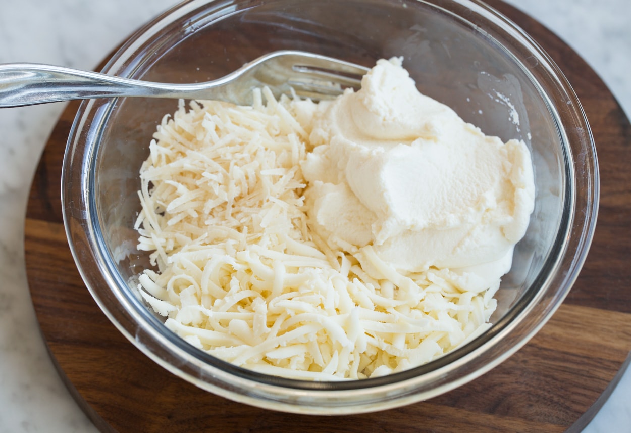 Mixing ricotta parmesan and mozzarella in a mixing bowl for lasagna soup.