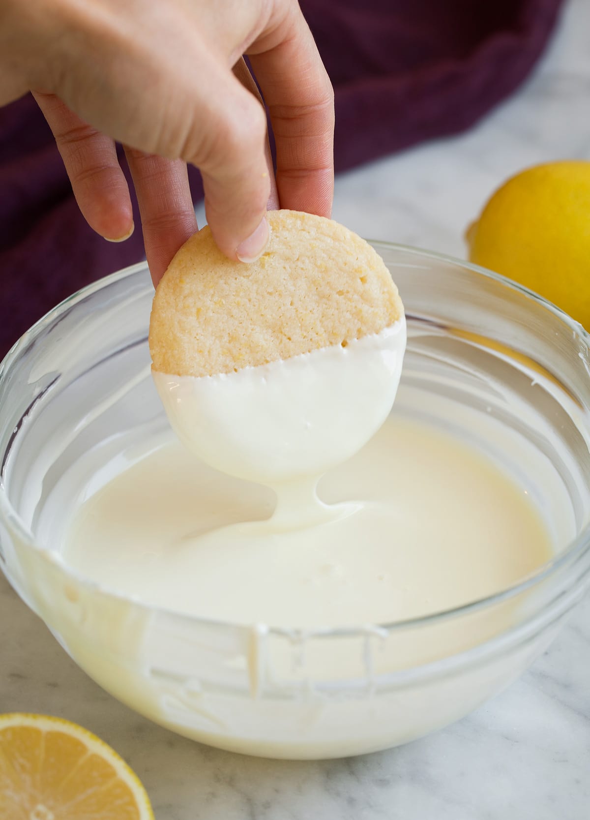 Dipping lemon shortbread cookies in melted white chocolate.