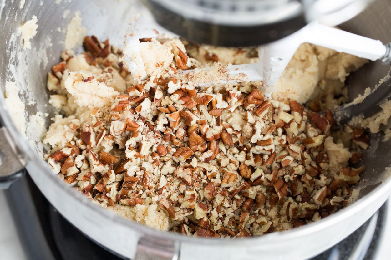 Adding Pecans to Mexican Wedding Cookie batter in stand mixing bowl.