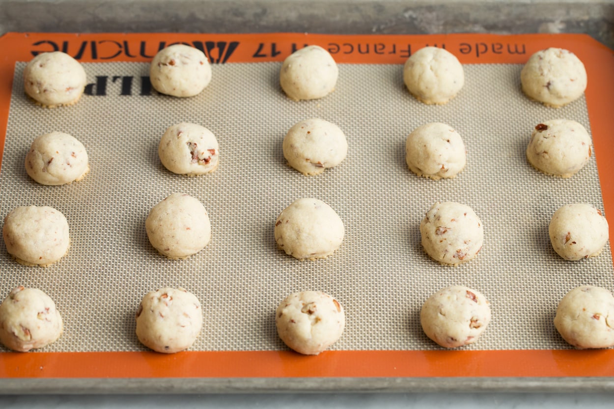 Twenty Mexican Wedding Cookies after baking on baking sheet.