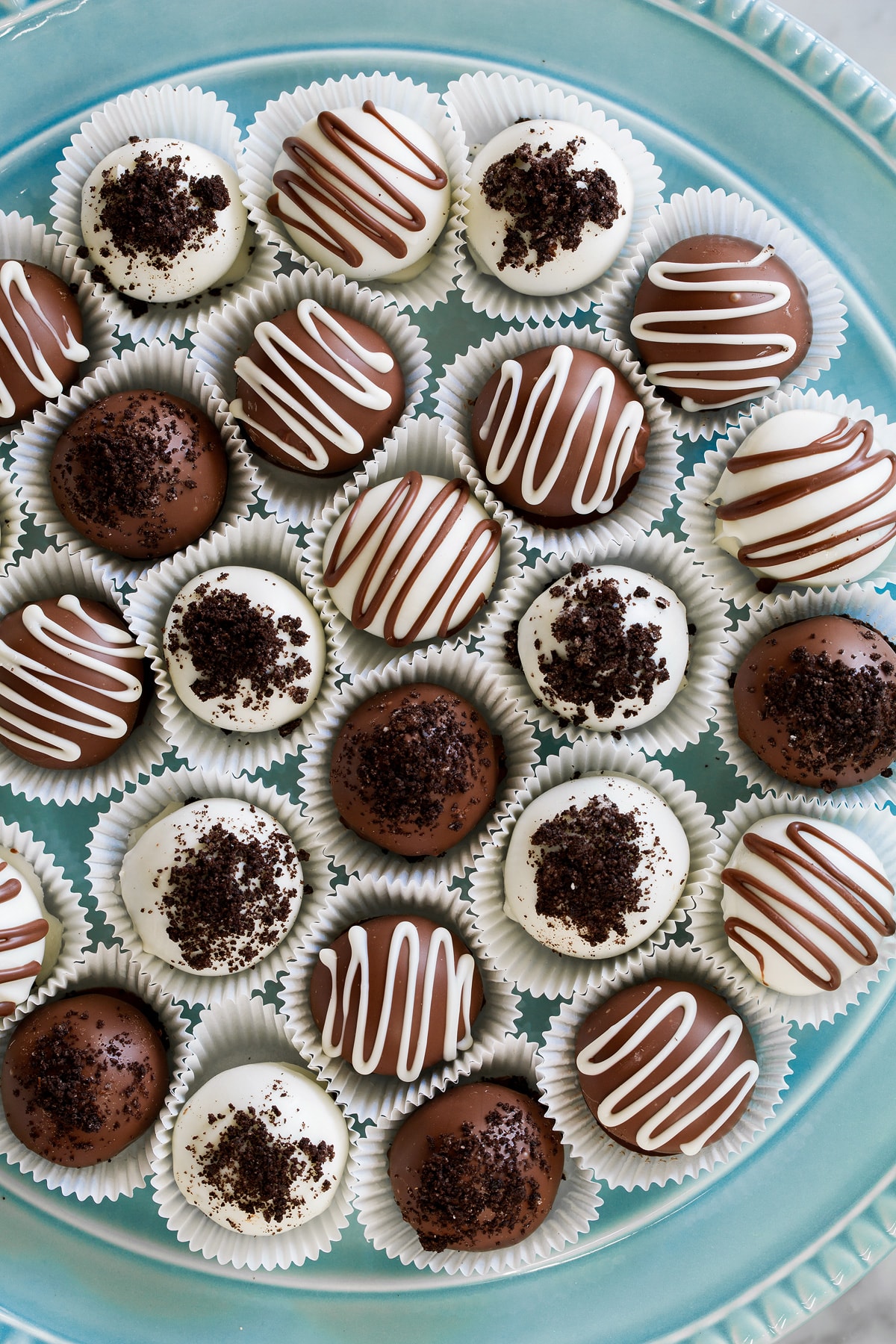 Overhead image of milk chocolate and white chocolate covered oreo balls on a blue platter.