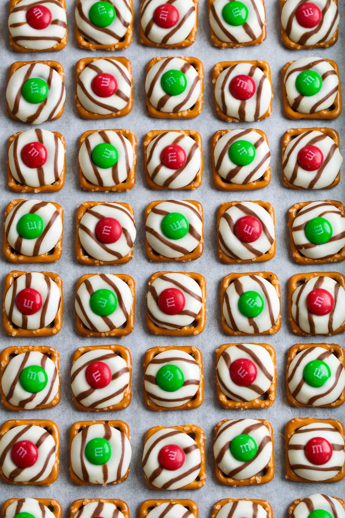 Pretzel Hugs Pretzel M&M Hugs in rows on parchment paper lined baking sheet.