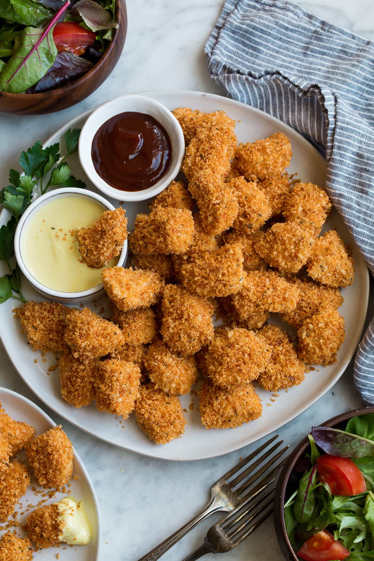 Chicken nuggets on a serving platter with a side of barbecue sauce and honey mustard.