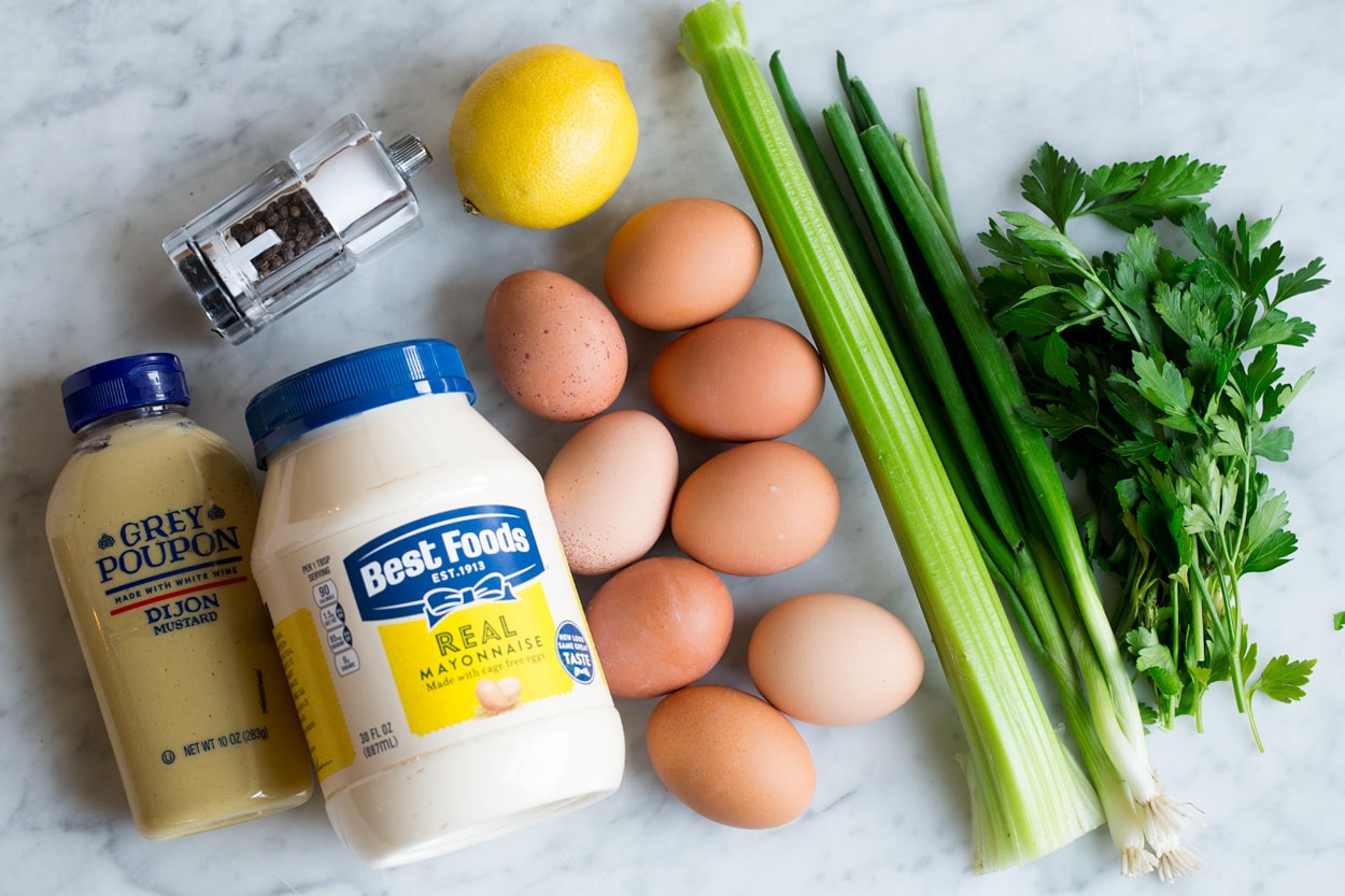 Egg Salad Ingredients needed for egg salad shown here including boiled eggs, mayonnaise, dijon, lemon, celery, green onions, parsley, salt and pepper.
