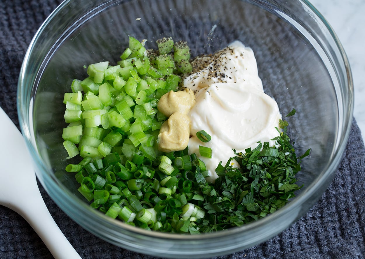 Egg Salad Showing how to make egg salad, mixing mayonnaise, mustard, celery, green onions and parsley in a glass mixing bowl.