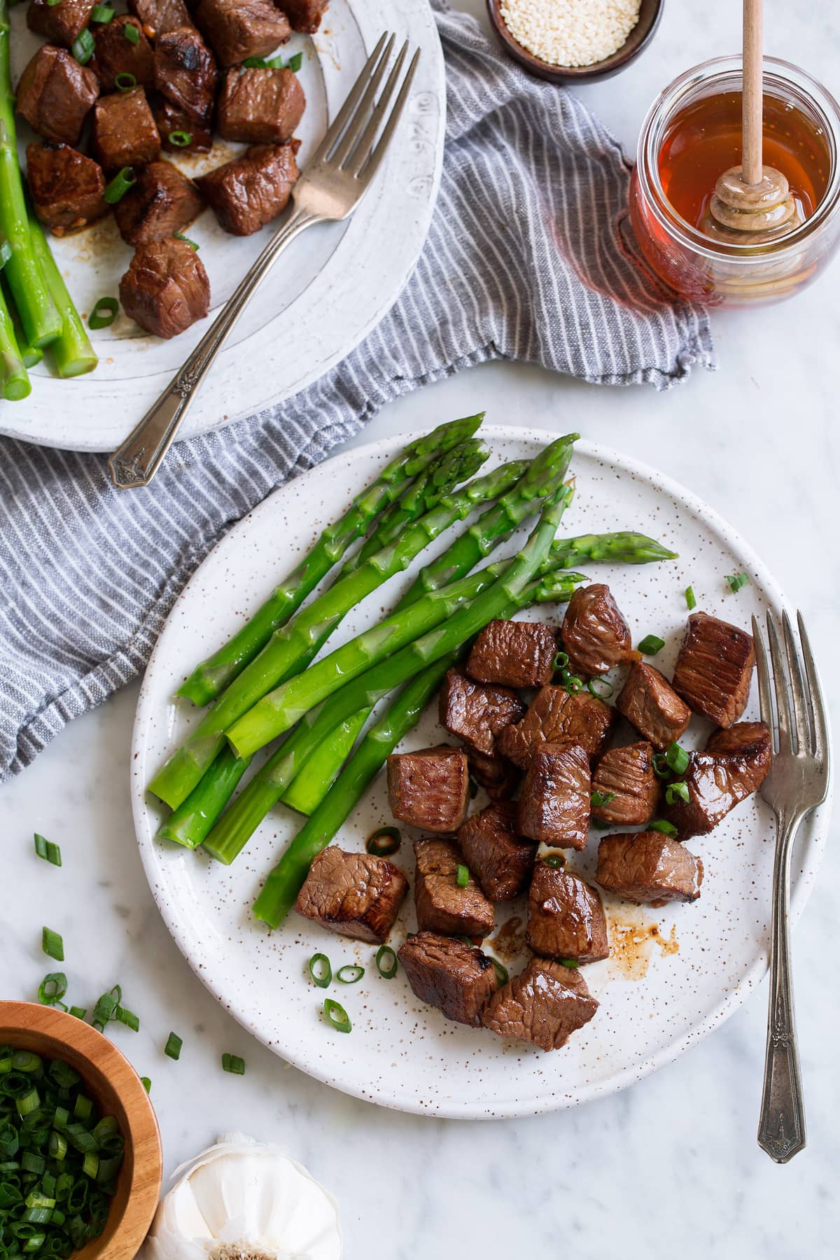 Single serving of Honey Garlic Steak Bites on serving plate with asparagus
